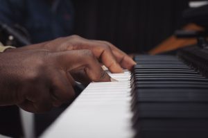 mãos de um homem negro tocando um teclado eletrônico